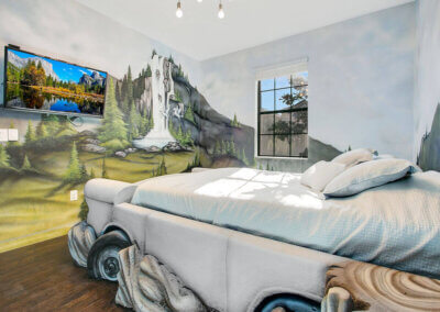 Bedroom with a white car bed and beautiful mountain scenery painted on the walls with wall-mounted TV